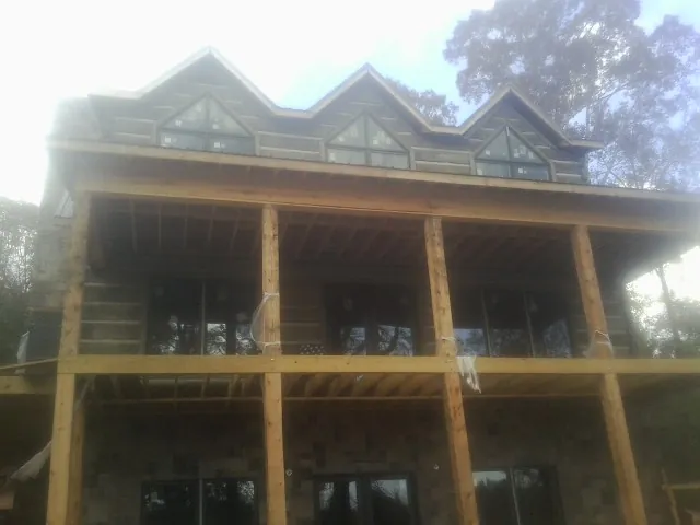 Dormers and porch framing on a large log home under construction — Roof Coating work by our crew in Long Beach